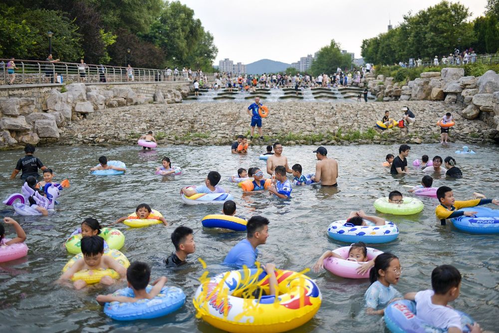 三伏天高温持续 滨水公园里戏水纳凉